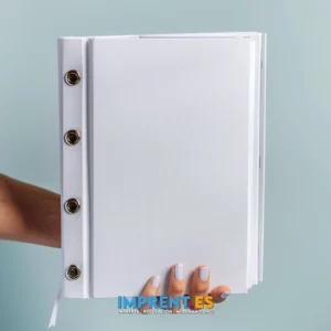 Mano sosteniendo un portafolio blanco con espirales metálicos, representando soluciones profesionales de merchandising