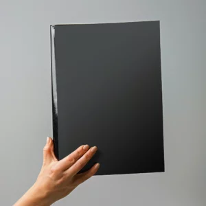 Mano sosteniendo un portafolio negro con textura mate, representando soluciones profesionales de merchandising